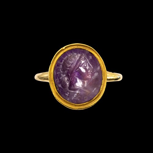 A Roman amethyst intaglio set in a later gold ring. Head of Helios.